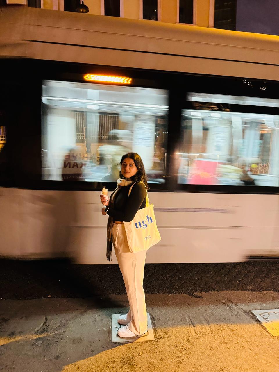 Woman standing beside a moving Istanbul tram at night